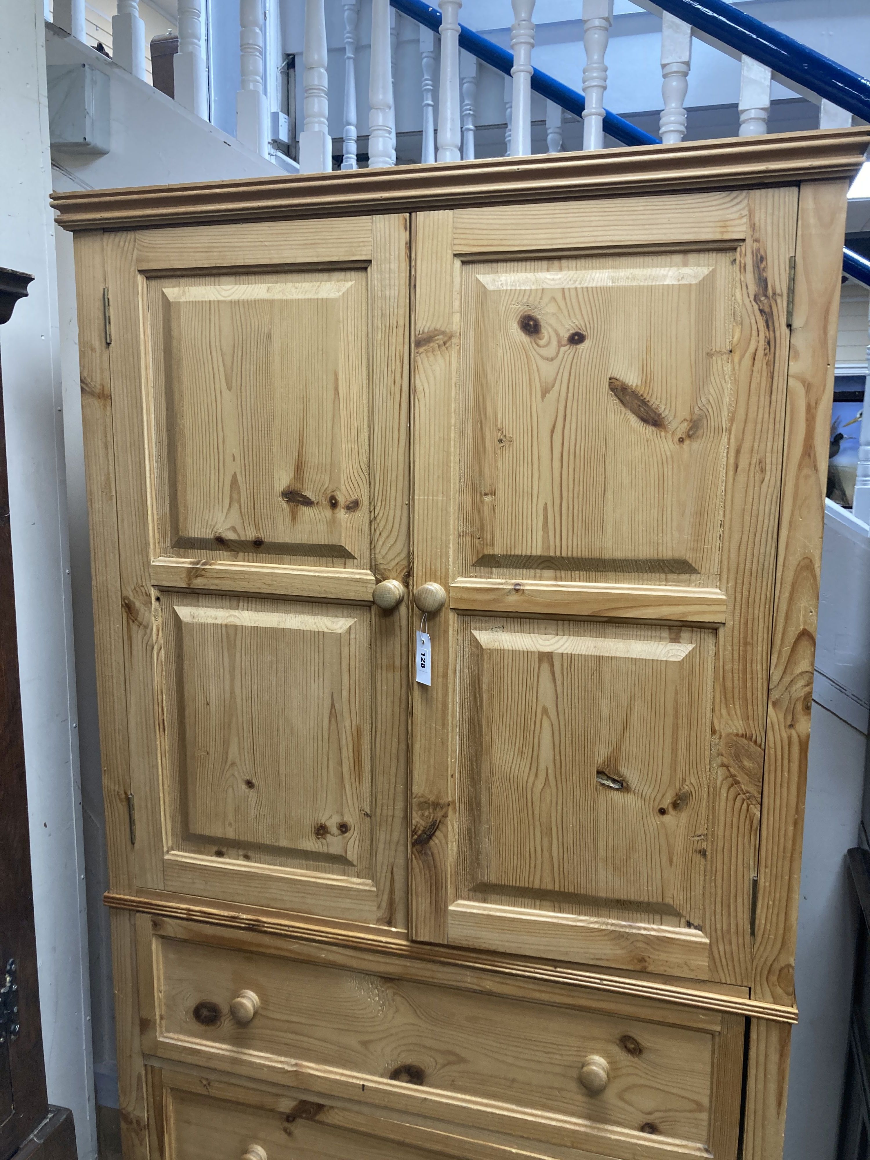 A contemporary pale pine press cupboard with twin panelled cupboard doors over a base fitted with three long drawers, height 199cm, width 105cm depth 57cm